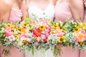 bride and bridesmaids holding pink and yellow wedding bouquets